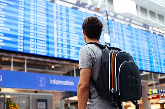 Viajante olhando no aeroporto Flight Monitor via Shutterstock