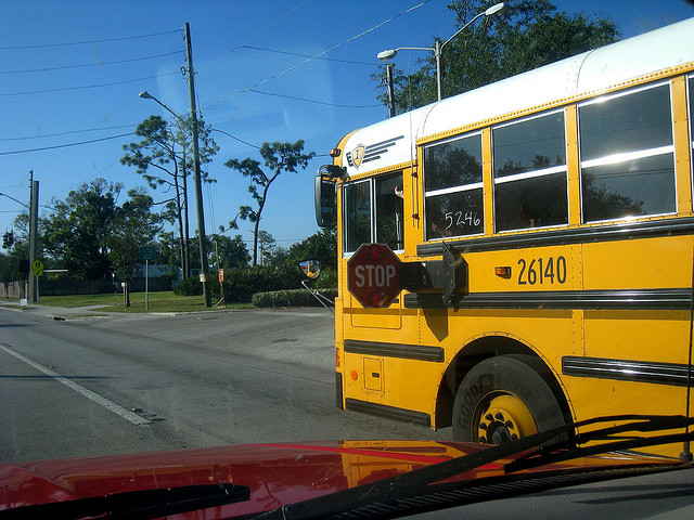 Placa de stop do ônibus escolar para fora sinalizando que todos devem parar. Foto do Flickr por Kate Warner.