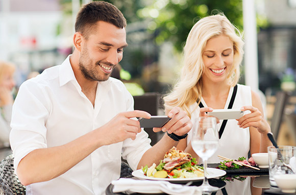 Foto: Pareja tomando fotos de comida a través de Shutterstock