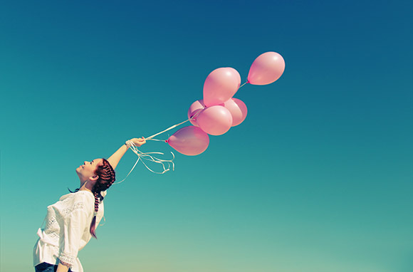 Photo: Woman Holding Balloons via Shutterstock