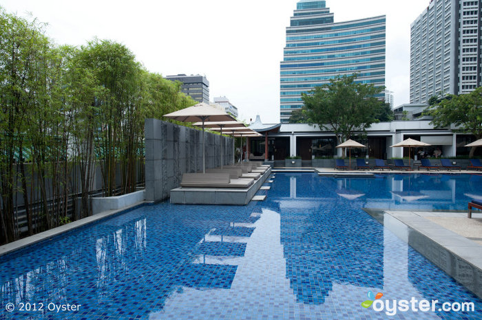 A piscina ao ar livre serena é cercada por cabanas em estilo pagode.