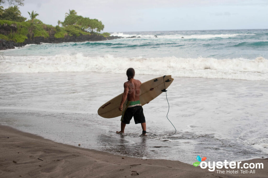 Um surfista solitário na praia de Hamoa no Travaasa Hana, Maui .