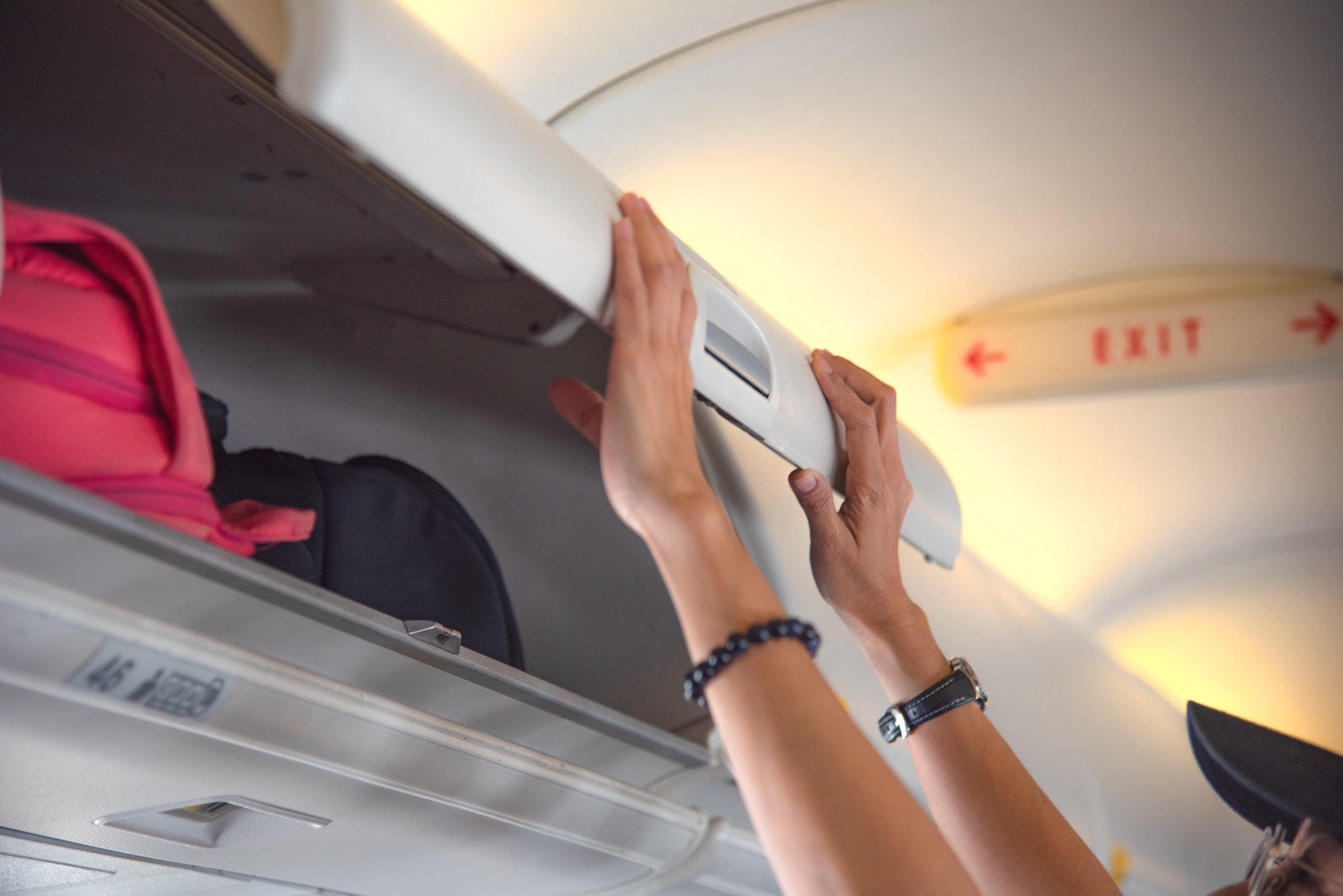 Close up of hands putting luggage in an overhead bin