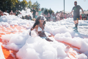 Woman sliding through bubbles with crowd in the background at Camp No Counselors in New York