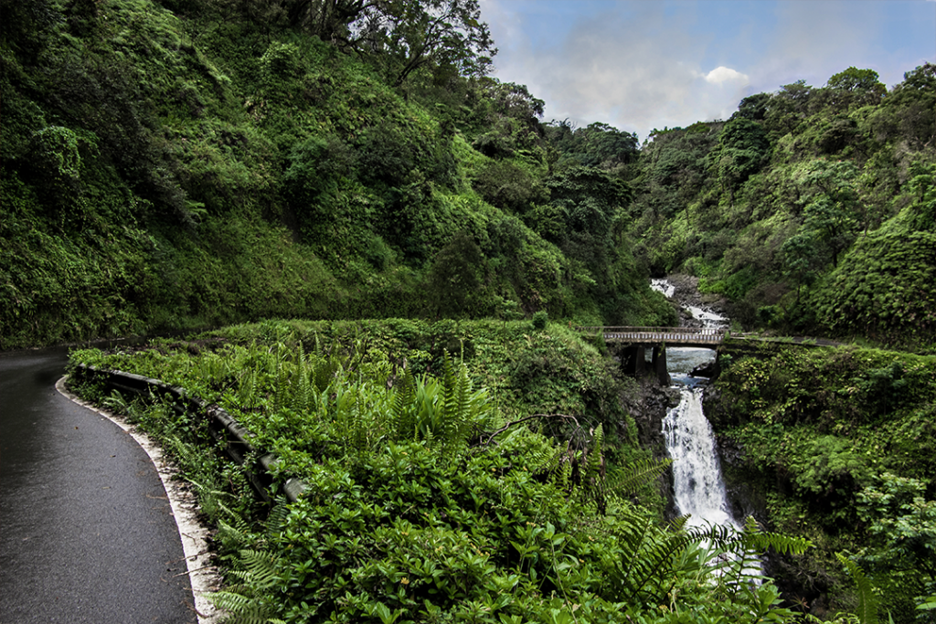 Road to Hana: The Hana Highway turns to cross a one lane bridge beside a waterfall on the north coast of Maui.
