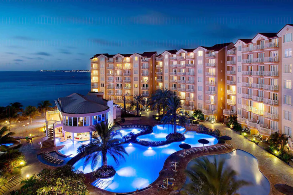 Exterior of the Divi Aruba Phoenix Beach Resort at night showing pool, pool house, and ocean