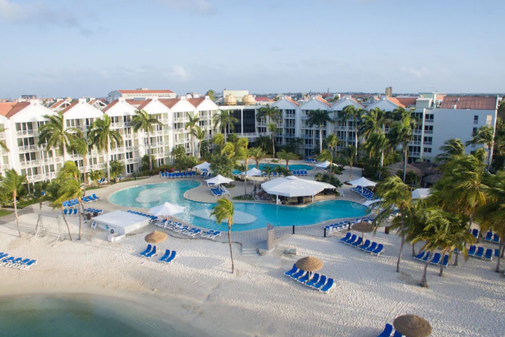 Aerial view of the Renaissance Wind Creek Aruba Resort looking from over the ocean at the hotel pools and building