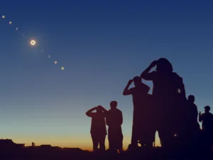 People are watching a solar eclipse in the sky with stars.